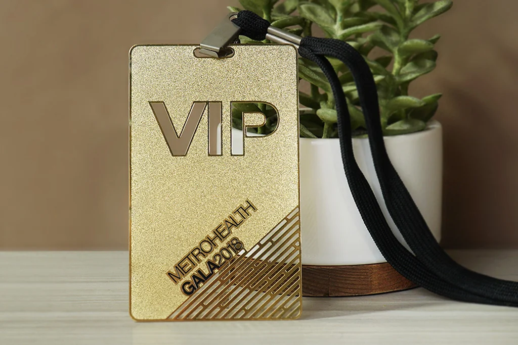Gold-tone metal VIP pass with cutout lettering